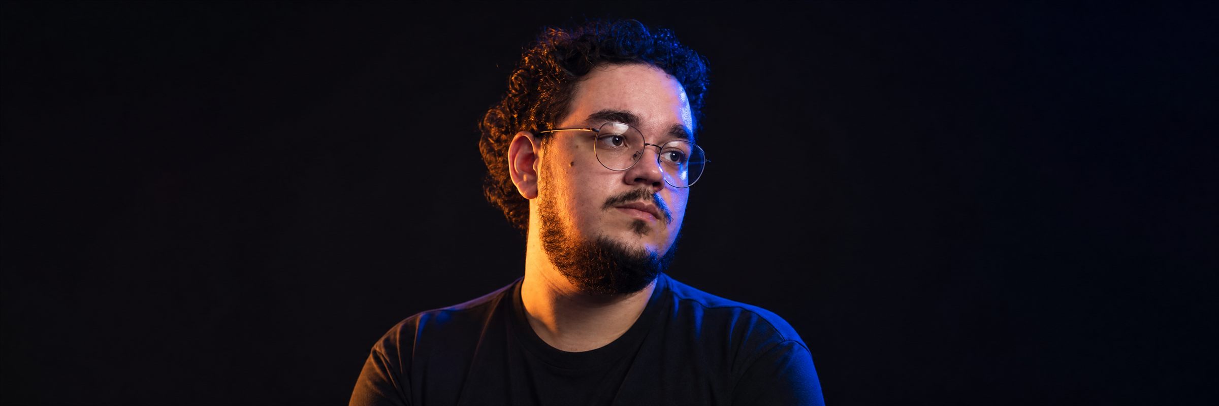 Caio Junior em retrato com iluminação azul e laranja